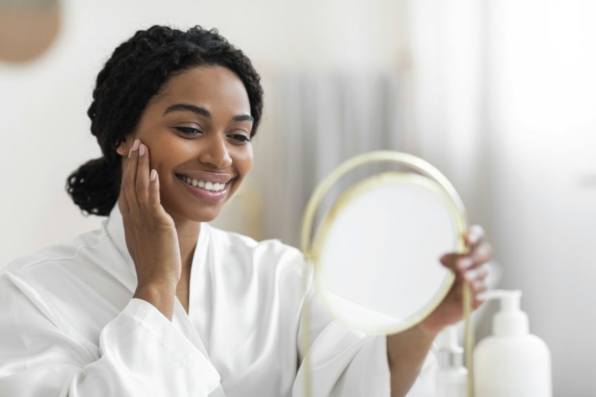 Attractive Black Woman Looking At Mirror And Touching Perfect Skin On Face