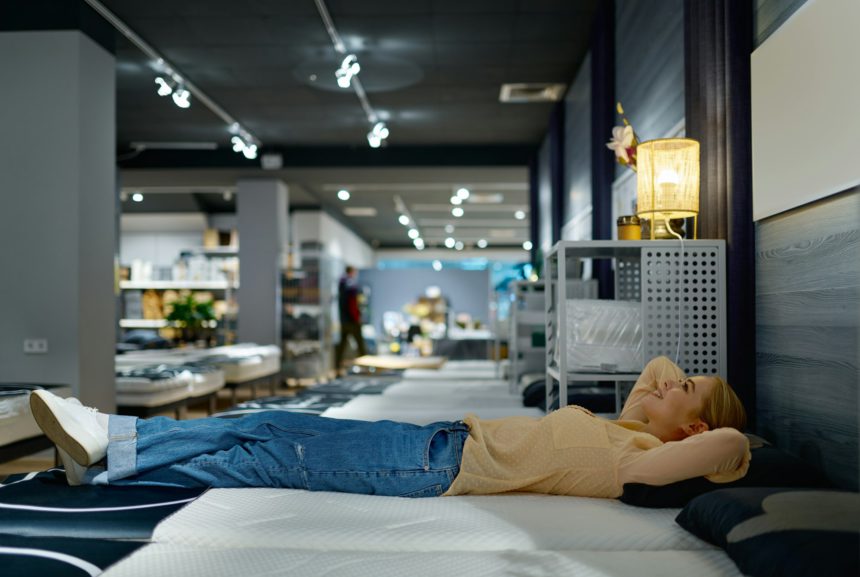 Woman choosing bed mattress in furniture store