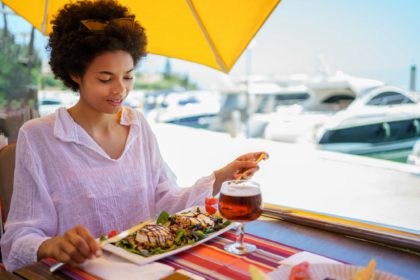 Young ethnic female having lunch in street restaurant